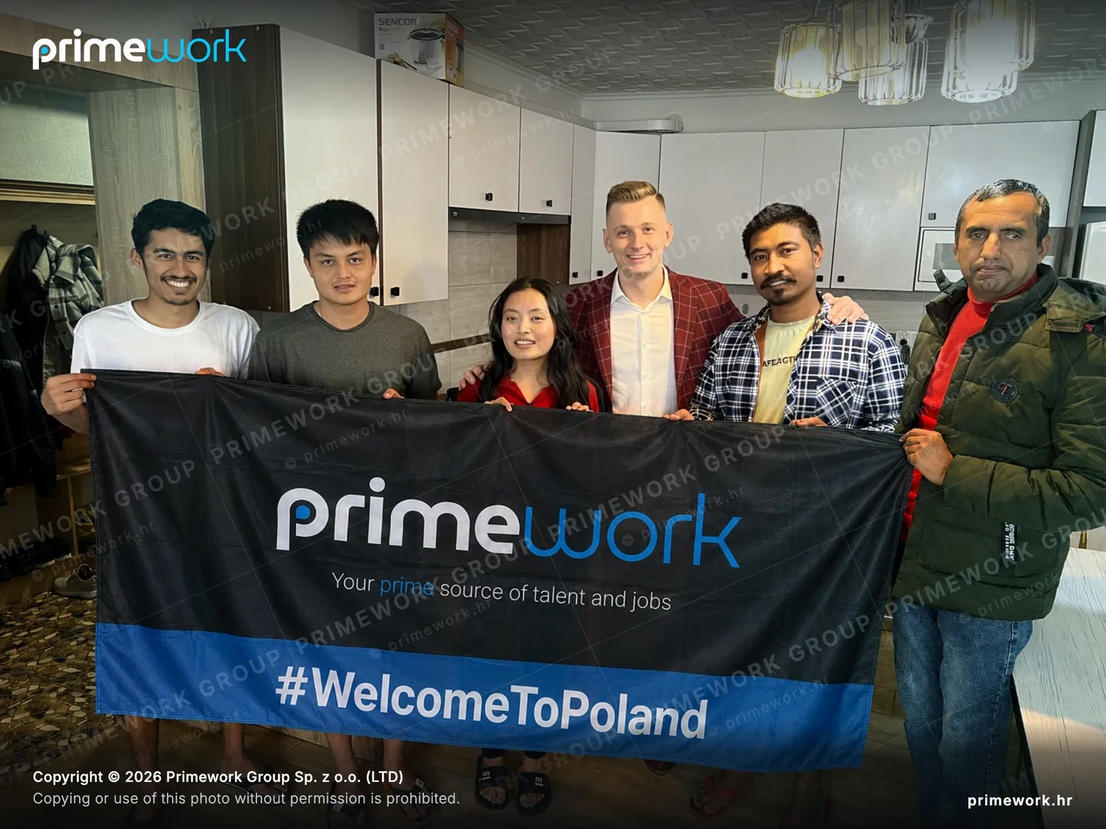 A foreign worker team with a Primework banner in a professional kitchen