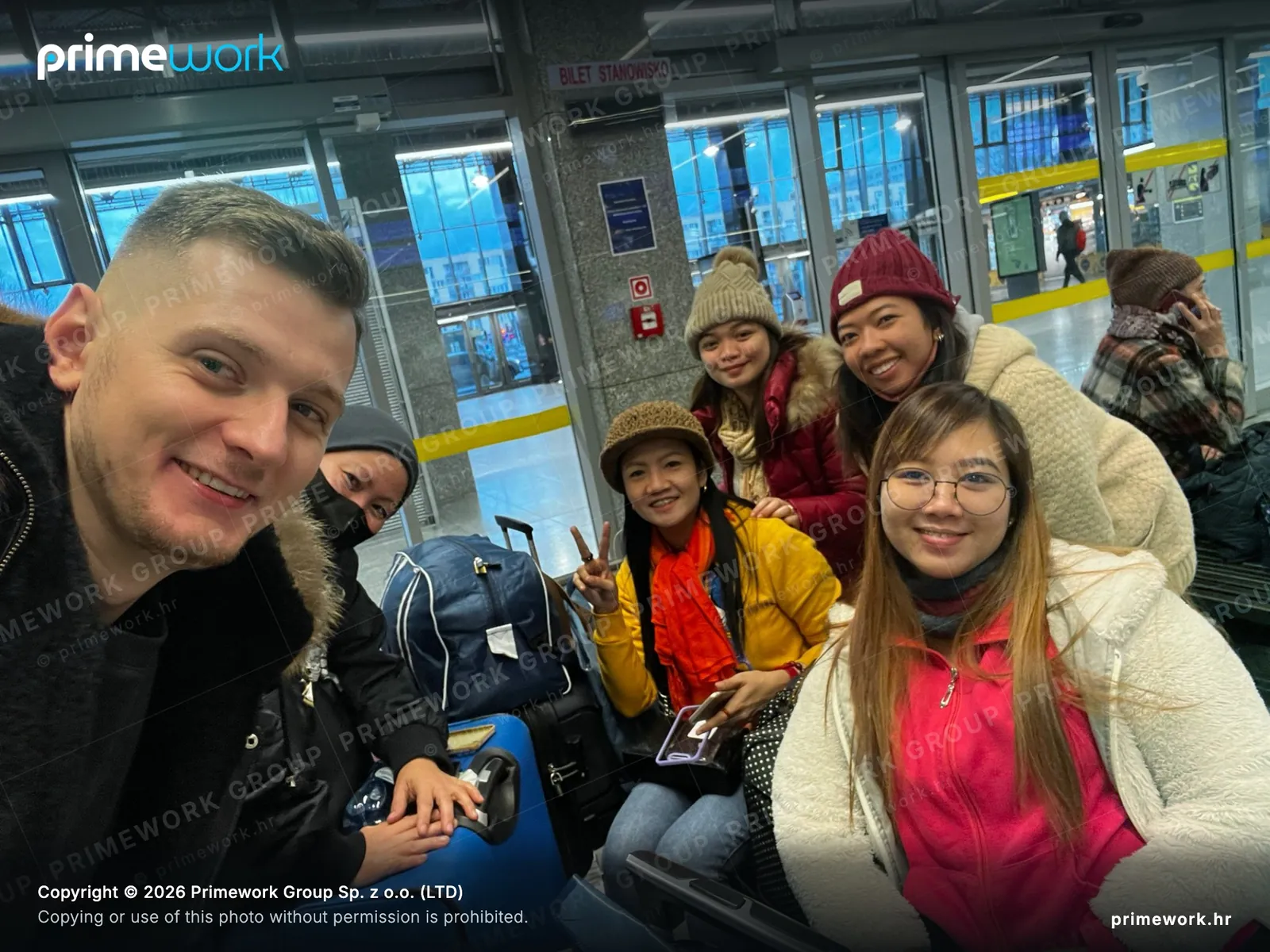 A Primework coordinator taking a photo with a worker group at a station