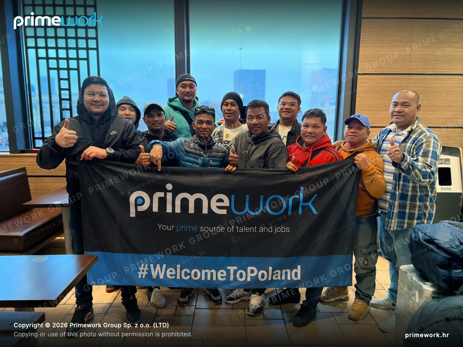 A foreign worker team with a Primework banner after arriving in Warsaw